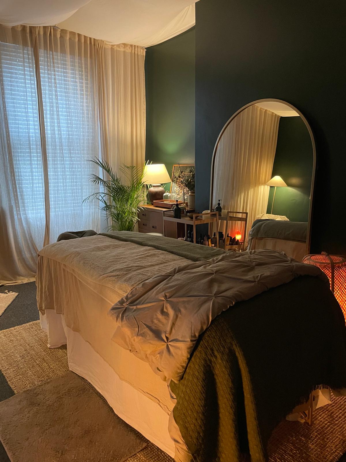 Treatment room with arched mirror, plant, and candlelit side table.